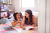 Happy mother and daughter drawing on bedroom rug