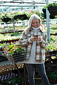 Happy female customer using smart phone in garden shop