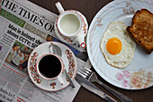 Spiegelei mit Röstbrot, Kaffee, Milch und die Frühstückszeitung