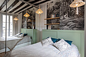 Queen bed with green painted headboard, wallpaper above and a closet with mirrored sliding doors
