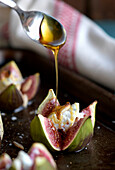 Drizzling honey on figs stuffed with goat cheese