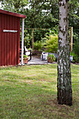 Blick vom Garten auf rot-braunes Holzhaus