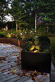Wooden terrace with illuminated raised beds made of rusty corten steel