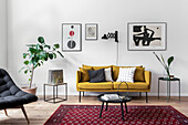 Mustard-yellow sofa and side tables below modern artworks on wall and potted ficus in living room