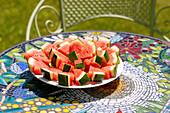 Teller mit Wassermelonen-Stücken auf Mosaiktisch im Garten
