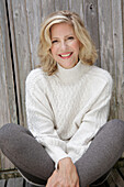 Mature blonde woman in white knitted jumper and grey leggings