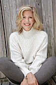 Mature blonde woman in white knitted jumper and grey leggings