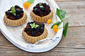 Vegan blackberry nougat tartlettes with almond sponge base