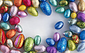 Colorful foil wrapped Easter eggs grouped around the edge of the picture