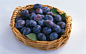Plums in a basket on a light background