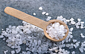 Coarse salt scattered around and in small wooden spoon