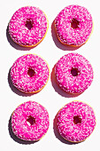 Donuts with pink icing on white background