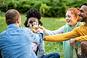 Happy young friends toasting drinks in garden