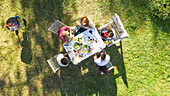 Happy young friends eating around a table in garden