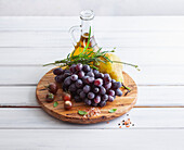 Grapes, pear, tomatoes, herbs, and oil on a wooden board