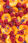 Aprikose und Himbeeren mit Lavendelblüten (bildfüllend)