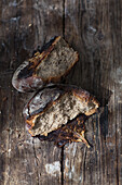 Frisch gebackenes Kohl-Speck-Brot, zerbrochen auf Holzuntergrund
