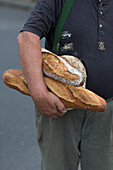 Mann trägt verschiedene Brote unter dem Arm