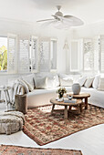 White seating furniture with linen cover, shutters and Moroccan carpets in the living room