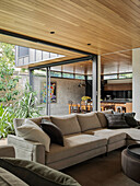 Living room with a sectional couch, in the background kitchen with dining area and inner courtyard