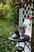 Autumn decoration with bust, concrete pumpkin, bird house, and ornamental apple on terrace