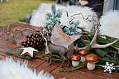 Terrace table decoration with wooden star, ceramic mushrooms, antlers, and cones