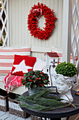 Winter decoration with berry wreath, American WIntergreen, bust, pine branches, and cushion on patio bench