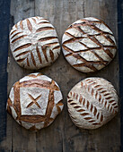 Four loaves of sourdough bread on a wooden base