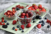 Summer berries and cherries in glass bowls on a tray