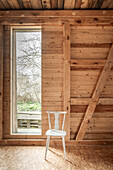 Chair in front of window in a room with wooden paneling