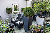 Elegante Terrasse in Grautönen mit Outdoormöbeln und Pflanzkasten