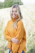 Junge blonde Frau in gelbem Rollkragenpullover in der Natur
