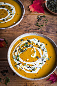 Pumpkin soup topped with a swirl of cream and pumpkin seeds