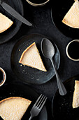 Lemon tart slices with cutlery and coffee on dark background