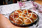 Homemade Easter traditional hot cross buns on ceramic dish with blossom flowers