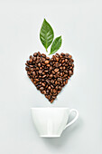 Weiße Kaffeetasse darüber Kaffeebohnen in Herzform