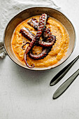 Close up of of grilled octopus tentacles, sweet potato puree, on a beige bowl