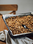 Homemade granola on big cooking tray on wooden table in kitchen