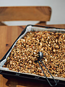 Homemade granola on big cooking tray on wooden table in kitchen