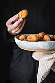 Potato croquettes being held by a woman in a black top, with copy space