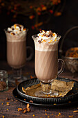 Two glasses of orange flavoured hot chocolate topped with whipped cream, orange zest and chocolate chunks.