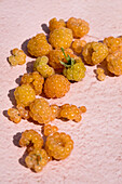 Heap of ripe golden raspberries placed on pink surface