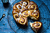 Yummy brioche bread with sweet icing served on round grating on blue table