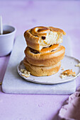 Tasty fresh buns stacked together on plate on marble board against lilac background during breakfast