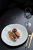 Appetizing beef with sweet potato puree served with tasty artichoke on white plate on black background