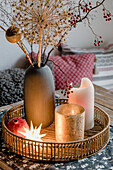 Christmas decoration with dried flowers, votive candle and a candle on tray