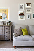 Antique dresser and a light upholstered sofa, with a picture gallery above it in the living room