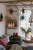 Weihnachtliche Deko mit Adventskranz, Blumenstrauß und aufgehängten Sternen im Esszimmer