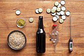 Zutaten und Utensilien für die Bierherstellung: Gerste, Flasche, Gärröhrchen, Kronenkorken, Thermometer