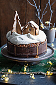 Schokoladenkuchen mit karamellisierten Nüssen, dekoriert mit Sahne und Lebkuchenhaus